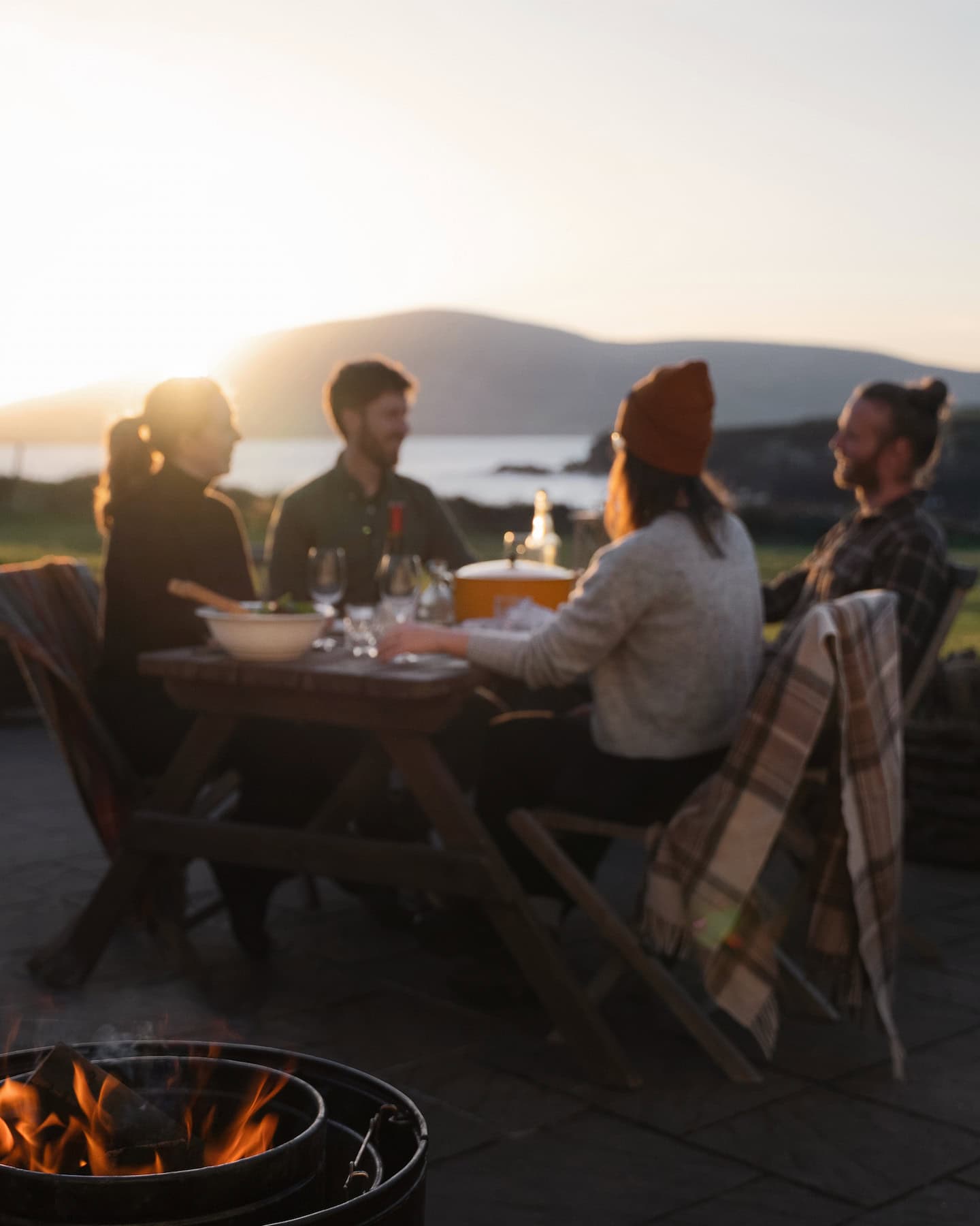 Guests enjoying a relaxed outdoor dinner at Sanctuary Cottages with views over Ventry Bay at sunset, reflecting the property's peaceful setting and amazing experience.