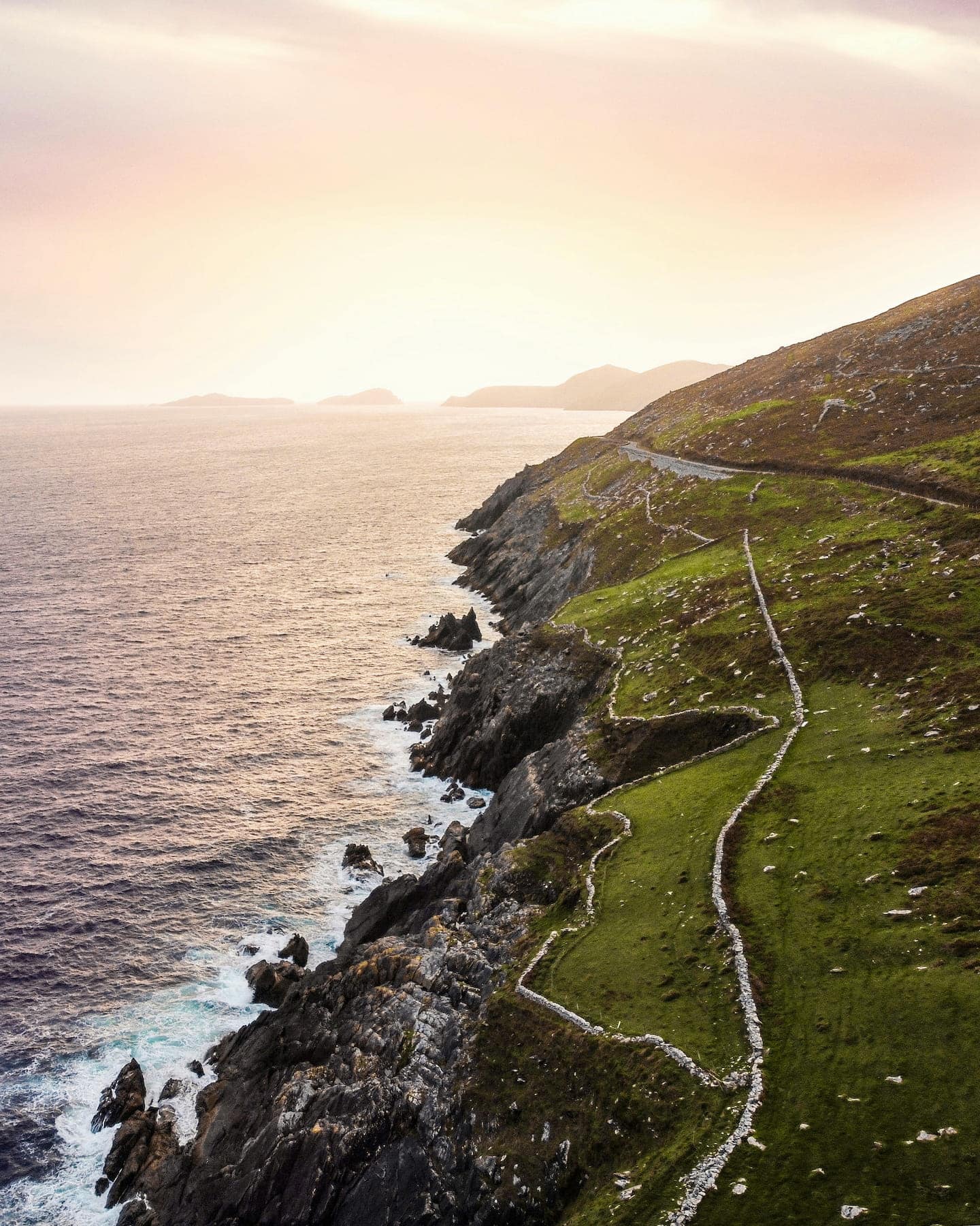 Sun setting over the Blasket Isles, with the famous road of Slea Head Drive weaving along the rugged coastline.